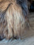A plush icelandic sheepskin with long brown and black wool in natural dark rusty tones, perfect for cozy decor