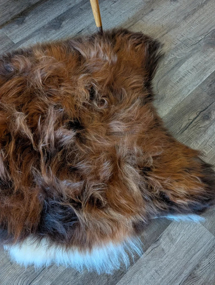 A plush irregular brown and black icelandic sheepskin rug with white fringe perfect for cozy wool icelandic decor