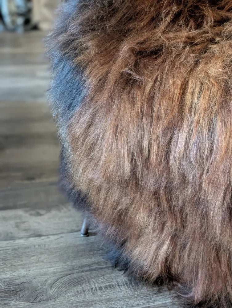 A plush brown and black faux fur ottoman with soft shaggy texture made from wool icelandic sheepskins