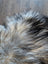 A plush multicolored faux fur rug with long wool icelandic texture in natural grey black and cream tones
