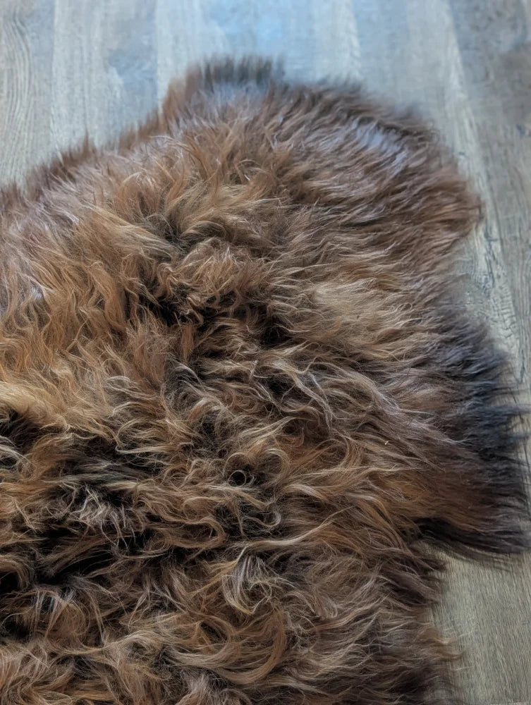 A plush naturally textured icelandic sheepskin rug in dark rusty brown tones perfect for cozy wool icelandic decor