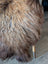 A plush curly brown and beige wool icelandic sheepskin-covered stool with wooden legs from fall6 collection