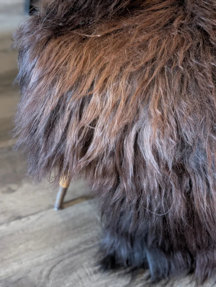 A plush shaggy brown and black wool icelandic sheepskin chair with a soft textured surface for cozy seating