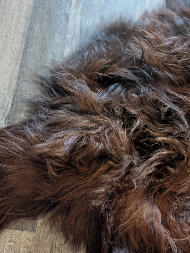 A plush shaggy brown wool icelandic sheepskin rug with soft textured surface and natural shade variations