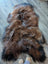 A plush irregular brown and black wool icelandic sheepskin rug with thick shaggy texture for cozy decor