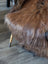 A plush brown wool icelandic sheepskin throw draped over a chair leg perfect for cozy fall decor