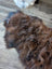 A plush irregular dark rusty icelandic sheepskin rug with soft wool icelandic texture and natural shade variations