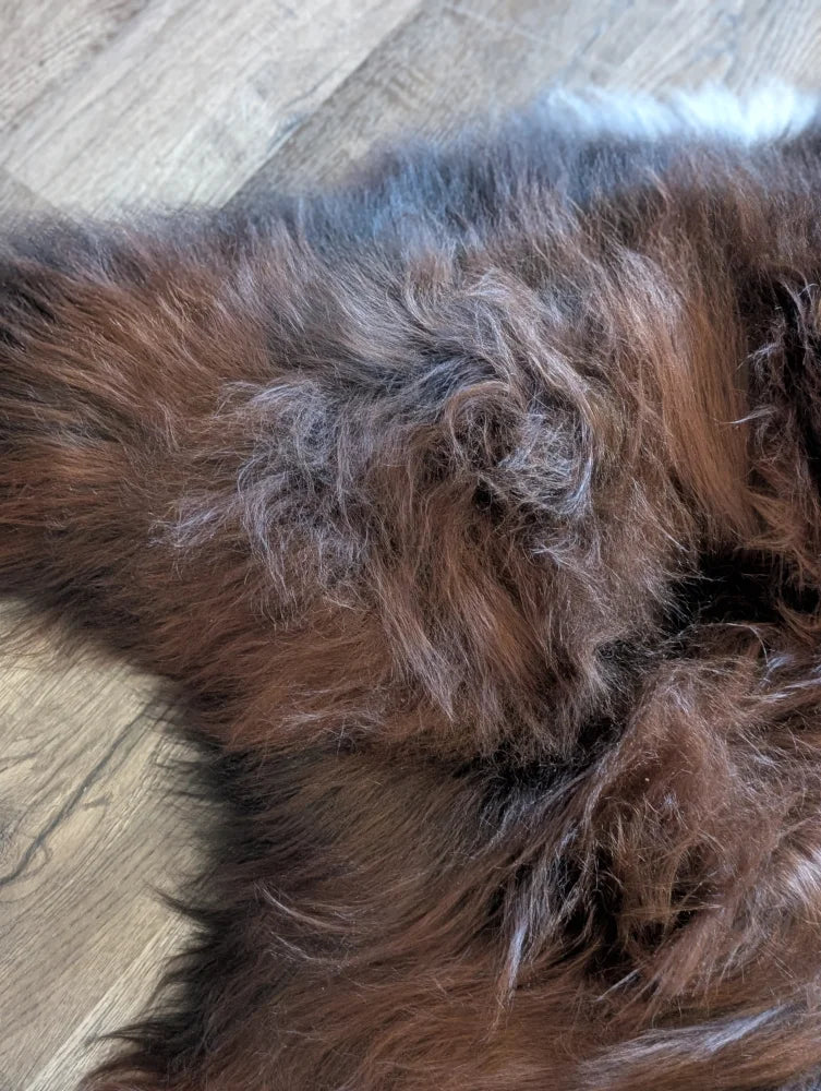 A plush 54 x 33 inch long-haired wool icelandic dark rusty sheepskin rug with soft textured surface for cozy use