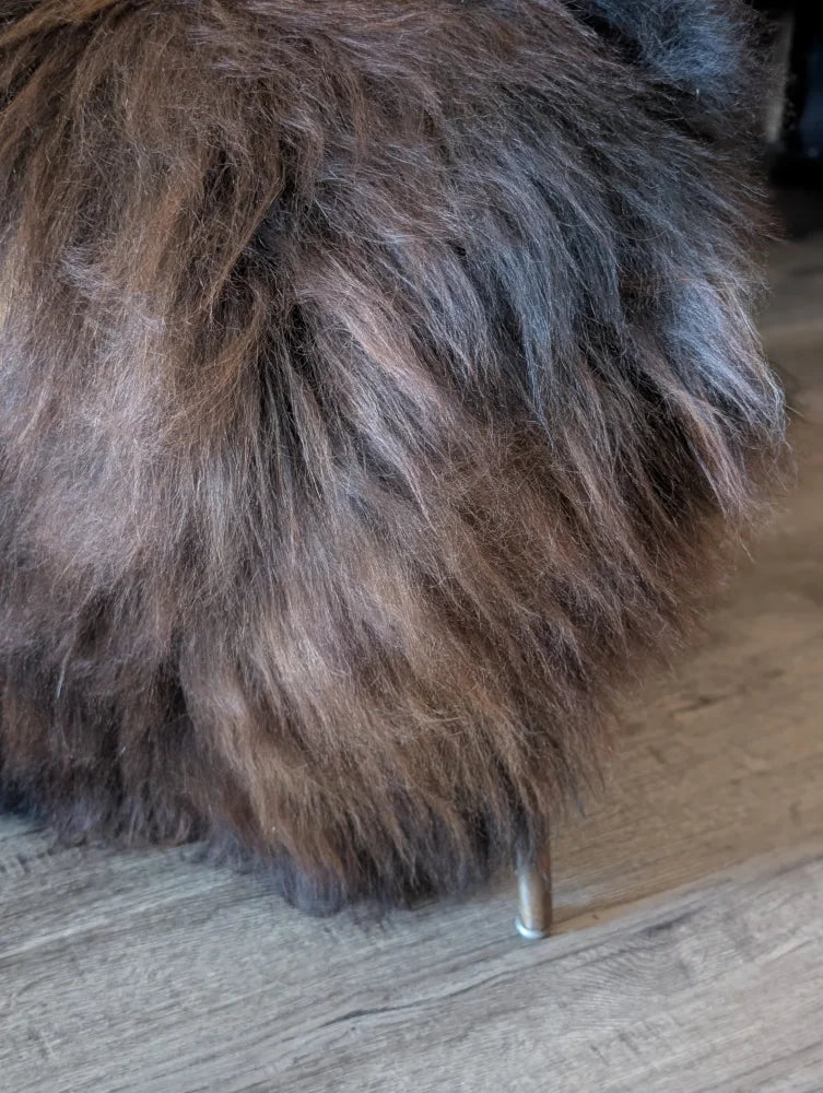 A fluffy cat sits on a massive natural dark rusty icelandic sheepskin perfect for cozy wool icelandic decor