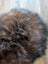A plush circular icelandic sheepskin rug in dark rusty brown and black with soft wool icelandic fibers