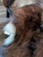 A plush brown faux fur tail with a white tip on a massive natural dark rusty icelandic sheepskin wool icelandic rug