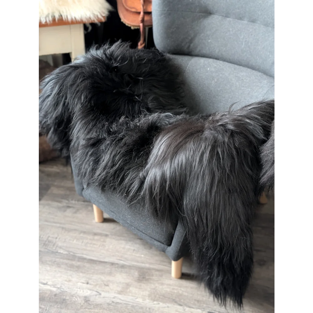 Black icelandic sheepskin throw draped over gray armchair perfect for cozy adds of icelandic sheepskin rugs