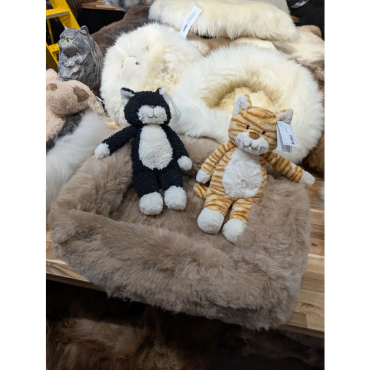 Cozy black and white plush cat on sheepskin pet bed