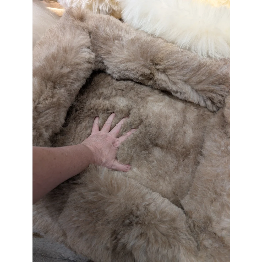 Cozy beige faux fur sheepskin pet bed with fringed plush edges