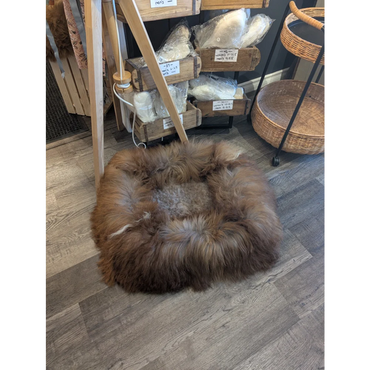 Round brown fur pouf ottoman with wooden legs and woven basket side table for sheepskin pet beds