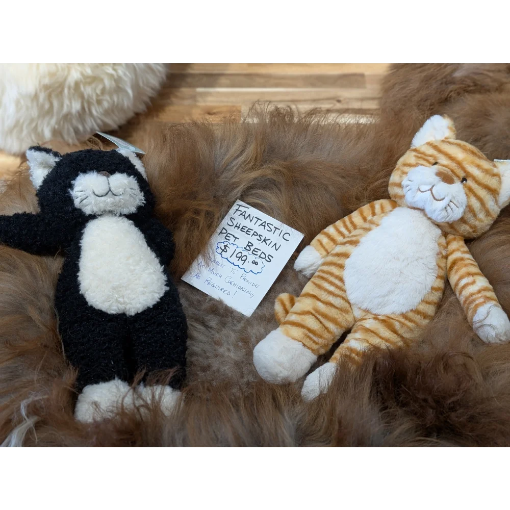 Cozy black and white cat plush on sheepskin pet bed