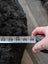Hand holding tape measure on thick black Icelandic sheepskin floor pouf