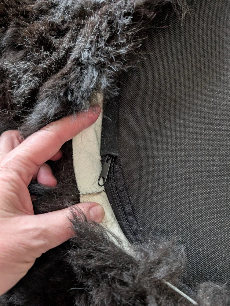Hand holding Icelandic sheepskin floor pouf wolf fur zipper pull