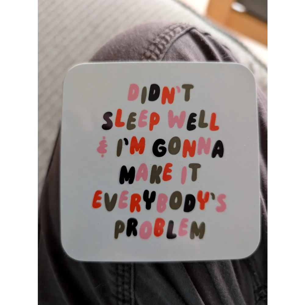 Funny White Coaster with Colorful Text on Sheepskin Rug by Angus Oliver