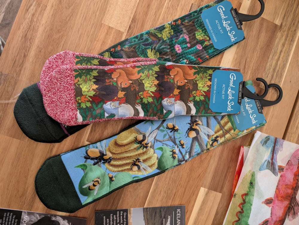 A pair of colorful good luck socks with forest and bee design on one and ice cream cone on the other