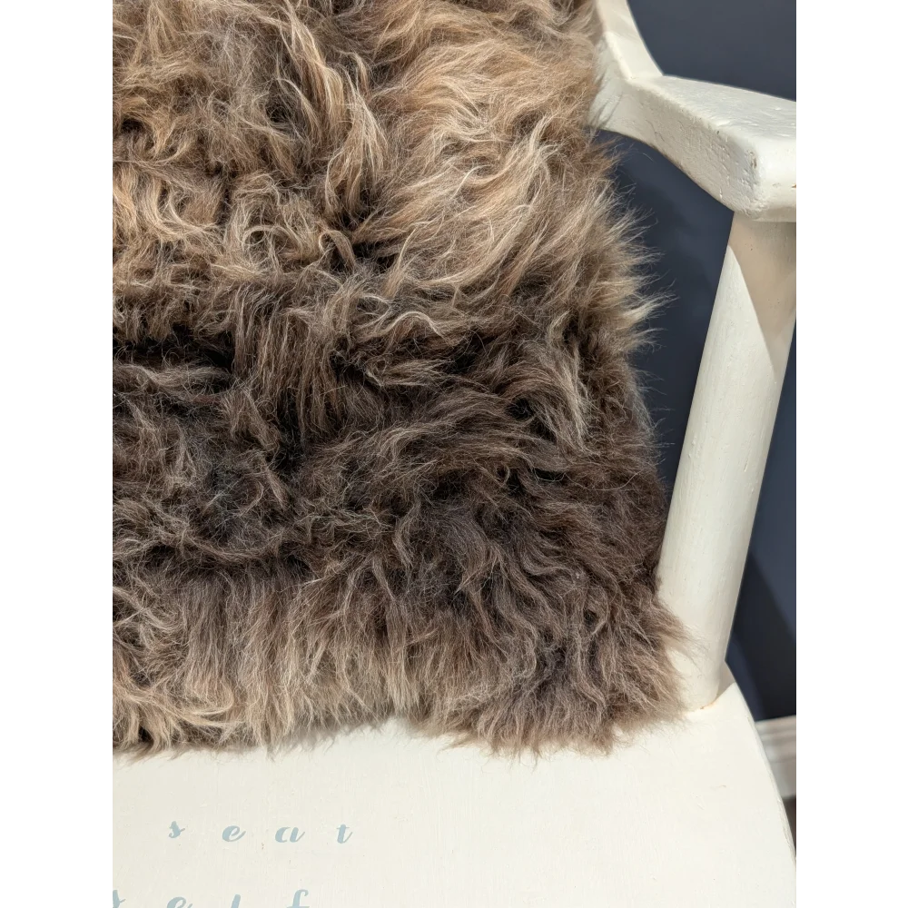 Gorgeous british sheepskin cushion with plush shaggy brown wool and soft curly texture on unbleached cotton canvas backing