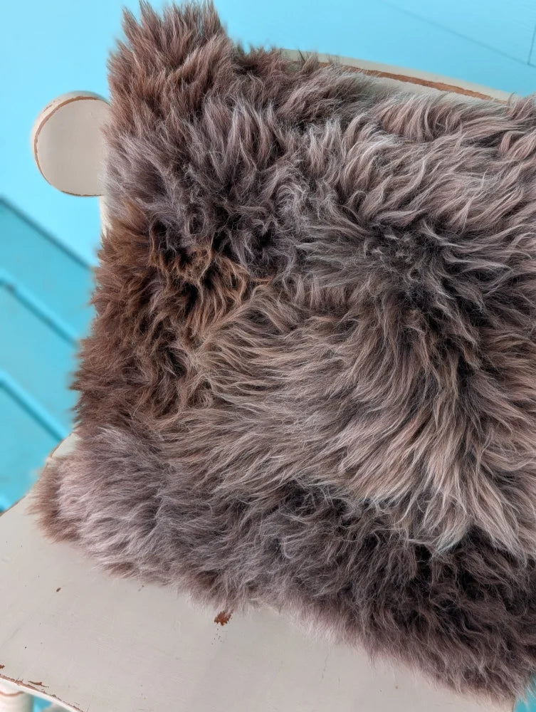 A gorgeous british sheepskin cushion with plush fluffy gray fur texture on unbleached cotton canvas by angus oliver
