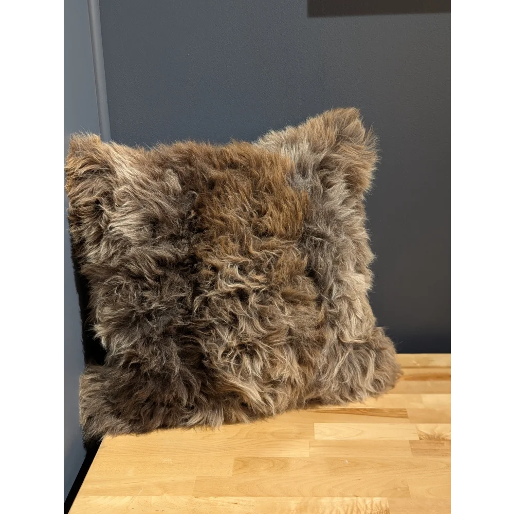 Gorgeous british sheepskin cushion with plush shaggy brown and gray curly texture on unbleached cotton canvas