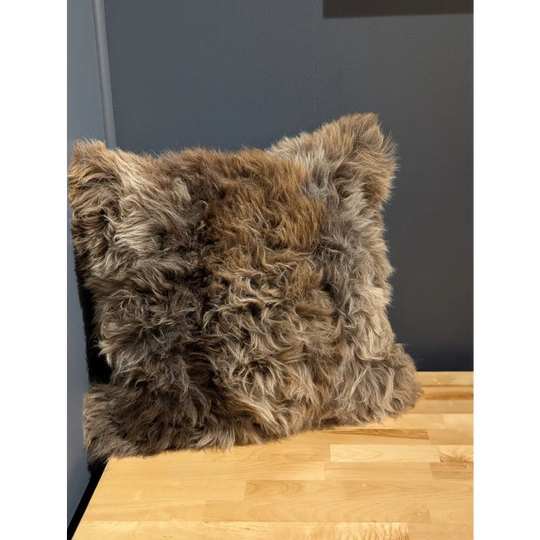 Gorgeous british sheepskin cushion with plush shaggy brown and gray curly texture on unbleached cotton canvas