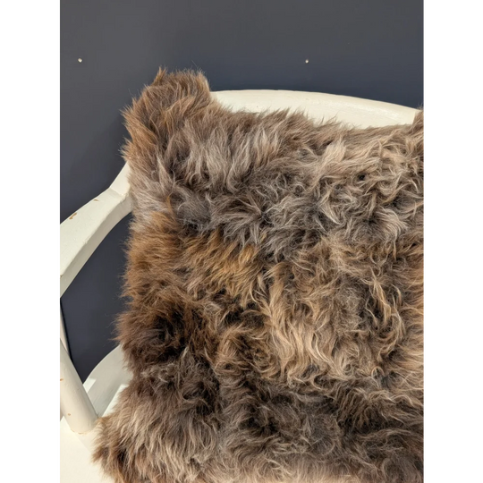 Gorgeous british sheepskin cushion with plush shaggy brown and gray curly texture on unbleached cotton canvas