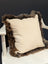 Cream-colored british sheepskin cushion with plush dark brown fur trim on unbleached cotton canvas fabric
