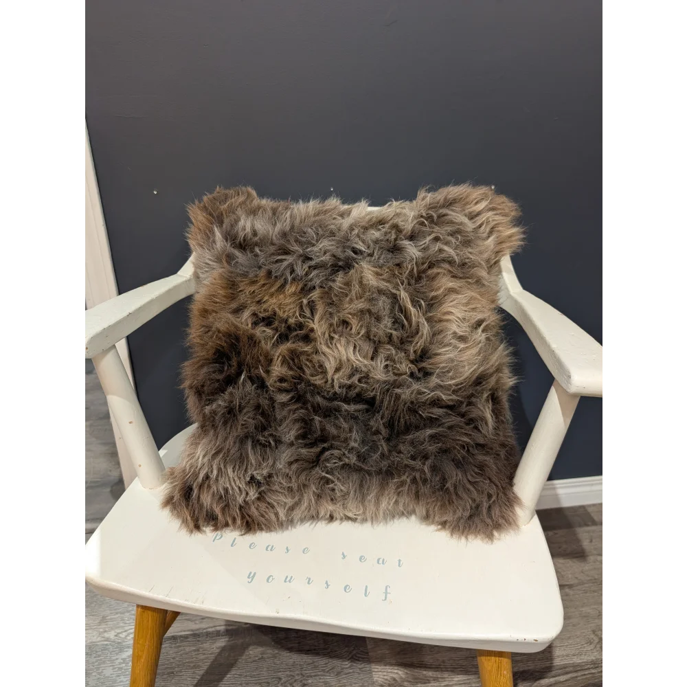Gorgeous british sheepskin cushion with plush shaggy brown texture on a white chair made with unbleached cotton canvas