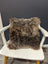 Gorgeous british sheepskin cushion with plush shaggy brown texture on a white chair made with unbleached cotton canvas