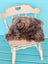 A gorgeous british sheepskin cushion in shaggy brown on a distressed white chair made with unbleached cotton canvas by angus oliver