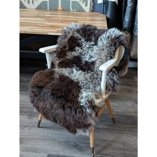 Gorgeous fluffy British sheepskin chair cover with natural spotted brown gray fur and wooden legs