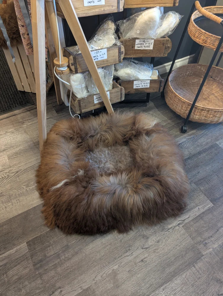 Round brown fur pouf ottoman with wooden legs and woven basket side table for sheepskin pet beds