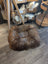 Round brown fur pouf ottoman with wooden legs and woven basket side table for sheepskin pet beds