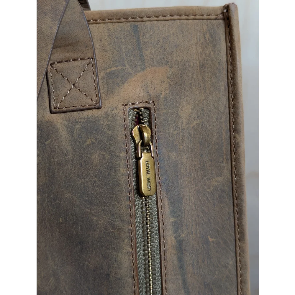 A brown distressed leather tote bag with hand-tooled leather accents and brass zipper pull loyal west in country medium bag style