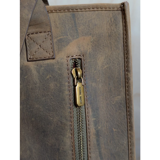 A brown distressed leather tote bag with hand-tooled leather accents and brass zipper pull loyal west in country medium bag style