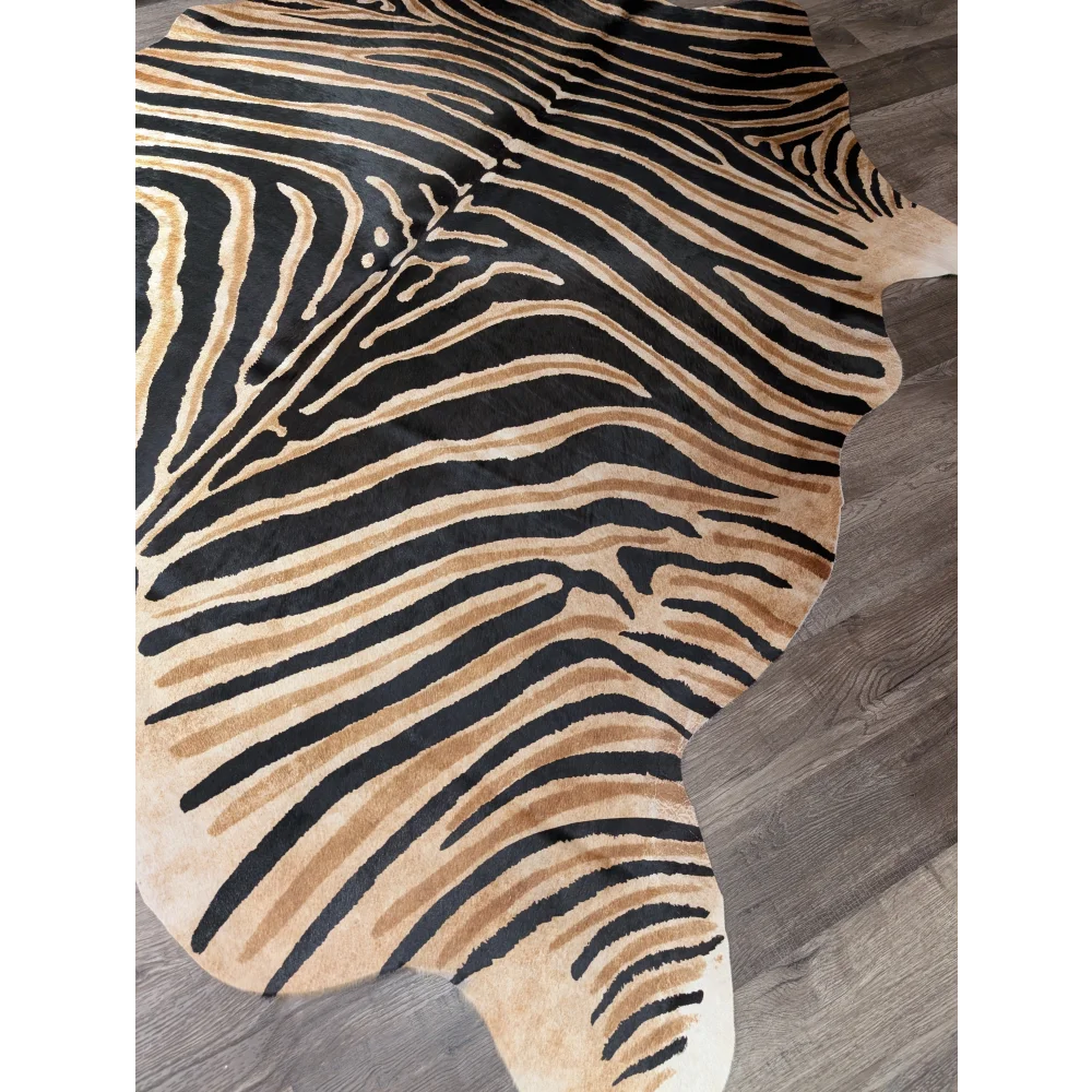 Gorgeous zebra printed cowhide rug by angus oliver with bold black and tan stripes on gray wood floor featuring unique characteristics
