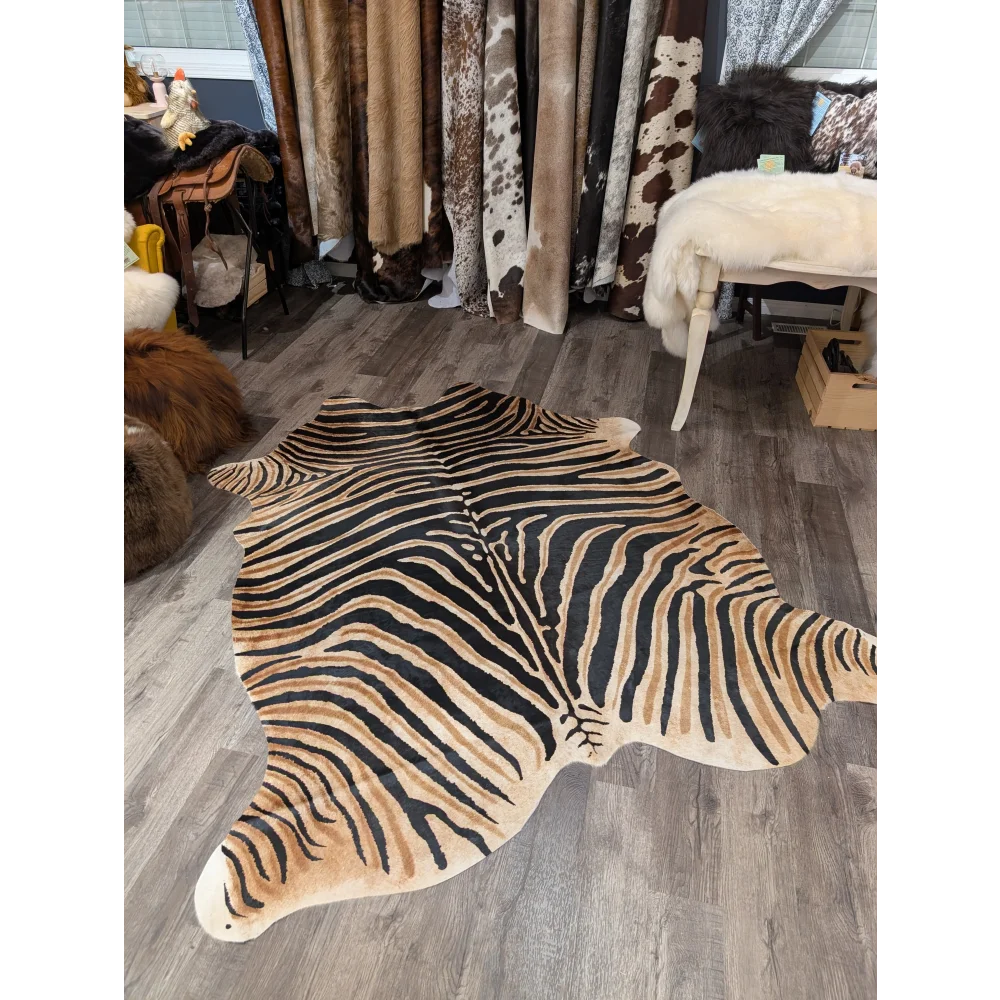 Gorgeous zebra printed cowhide rug by angus oliver with bold black and tan stripes and unique characteristics on wooden floor