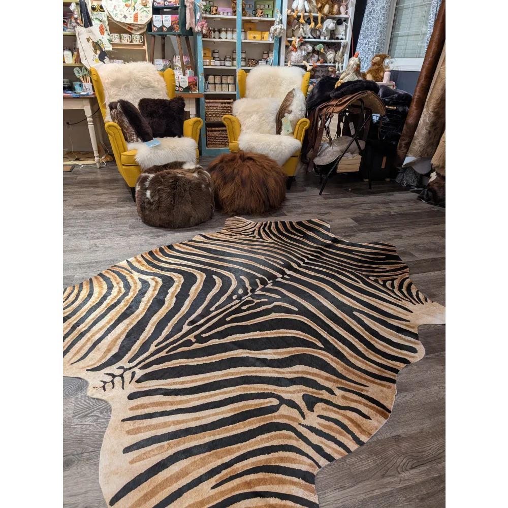 Gorgeous zebra printed large cowhide rug by angus oliver with bold black and tan stripes and unique characteristics on wood floor