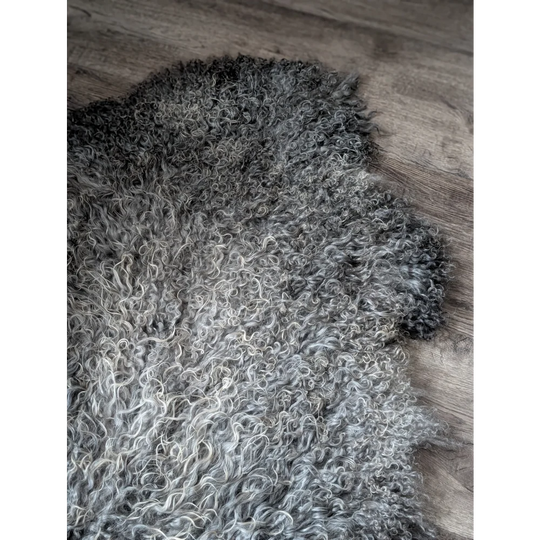 Gray and white curly Gotland sheepskin rug, 52x31, on wooden floor