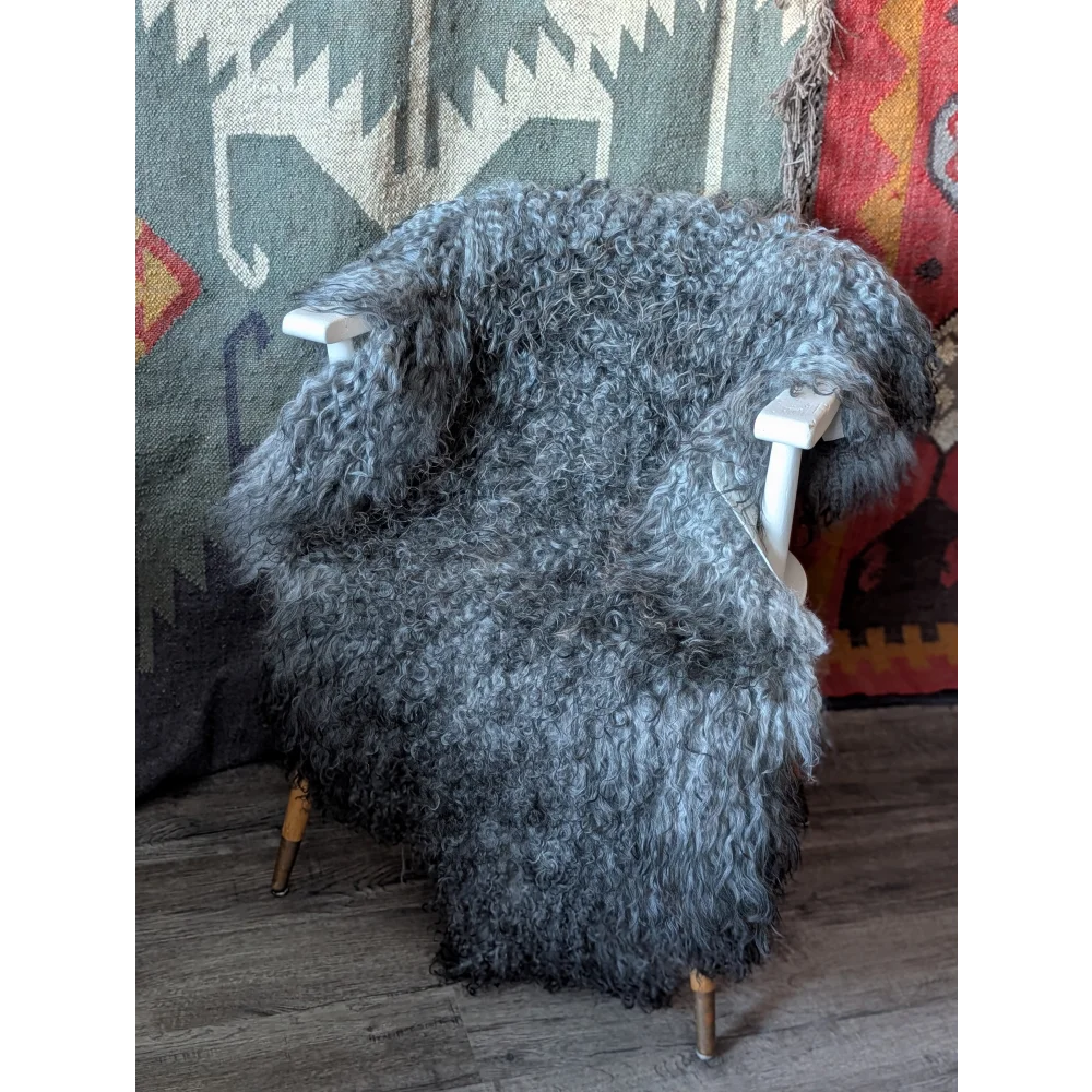 Plush gray curly Gotland sheepskin throw on white chair with brass legs