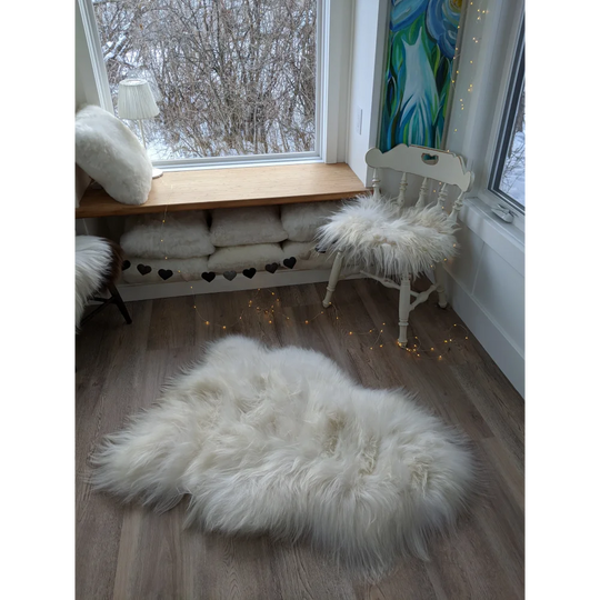 Grade a white icelandic sheepskin rug 53x34 inches with soft fluffy fibers on a wooden floor