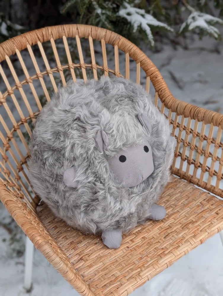 A soft gray rotund sheep cushion plush made from merino sheepskin by angus oliver with black button eyes and small ears