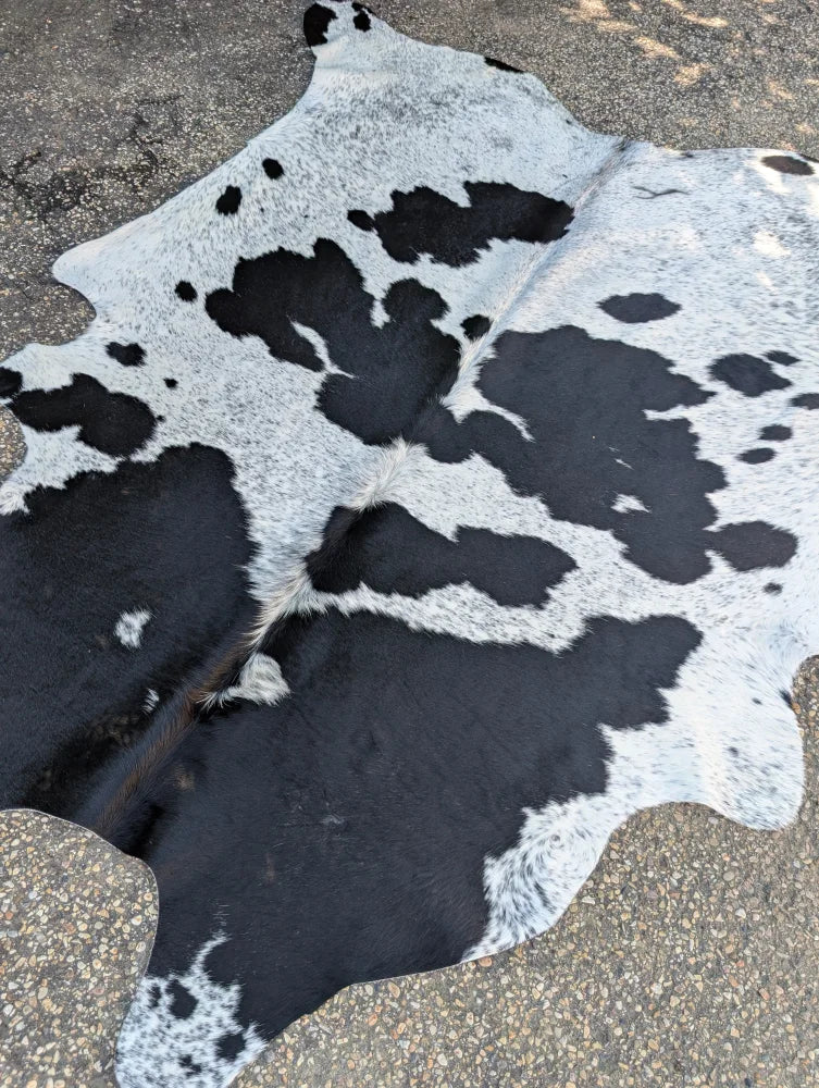 Large black and white cowhide rug with natural irregular patches showing unique characteristics and rustic charm