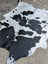 Large black and white cowhide rug with natural irregular patches showing unique characteristics and rustic charm