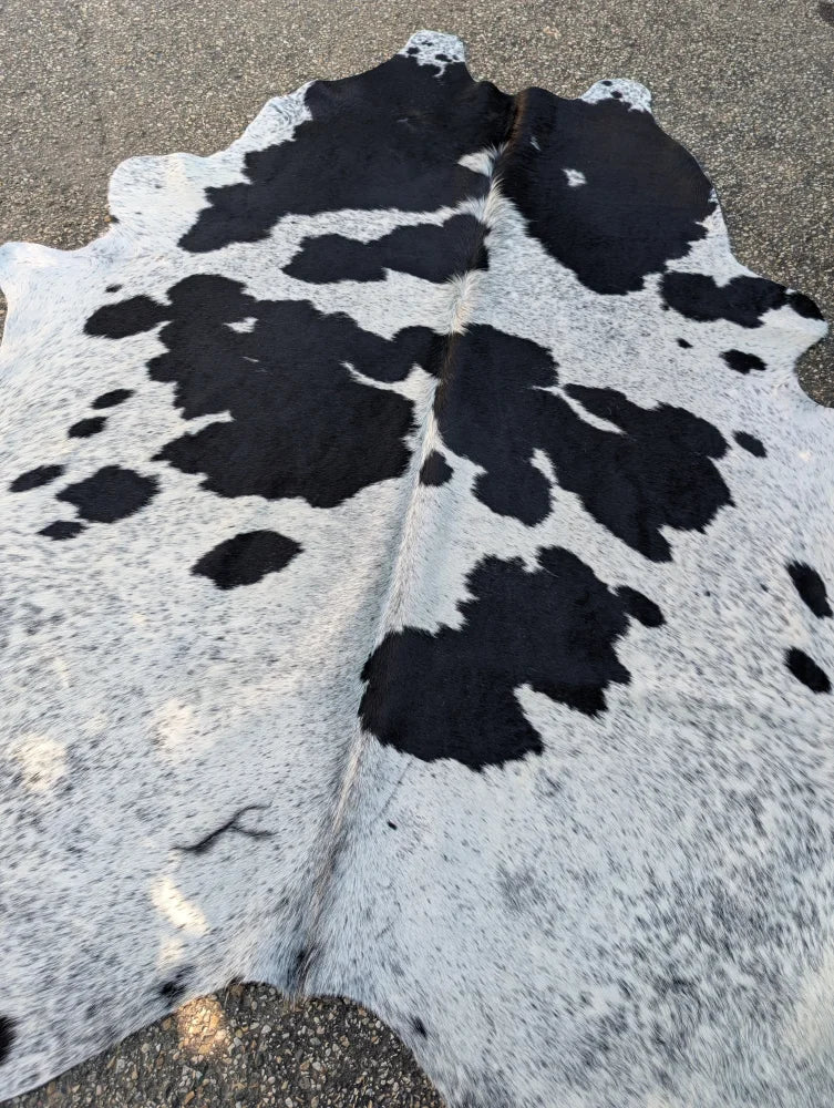 Large black and white cowhide rug hello10 with unique characteristics and rustic charm in a natural irregular pattern