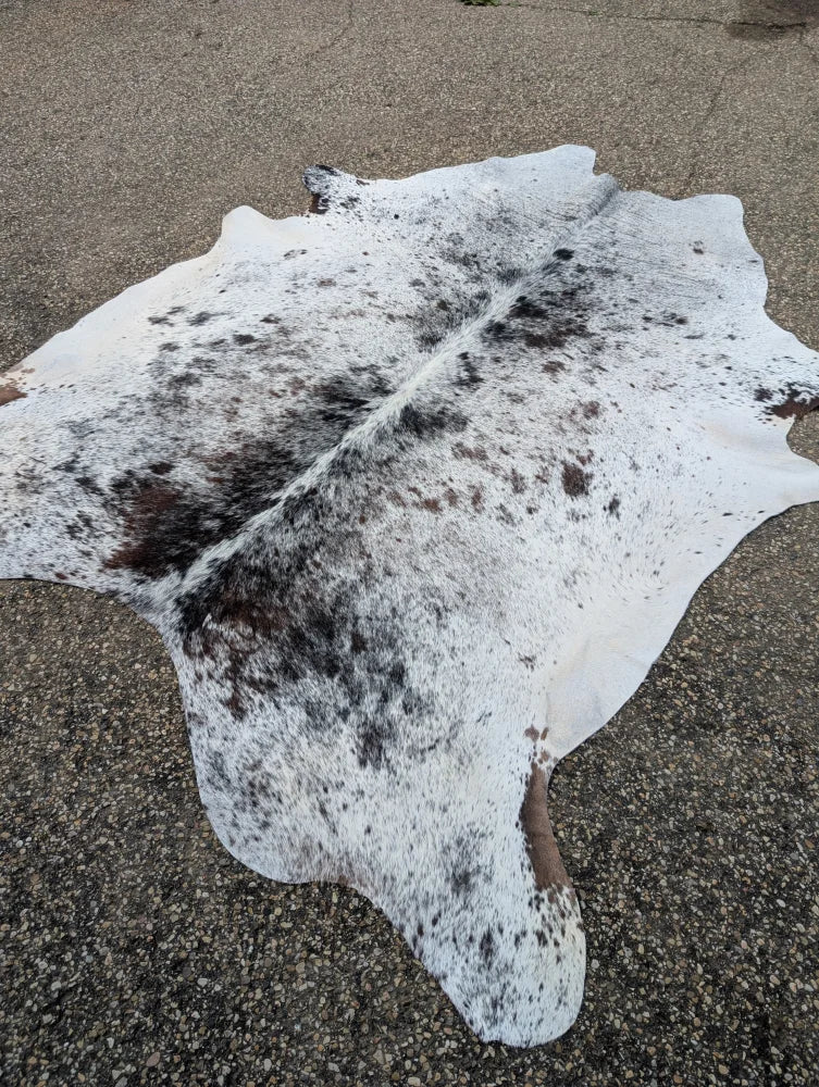 Large cowhide rug with white and black spots and natural fur texture showcasing unique characteristics