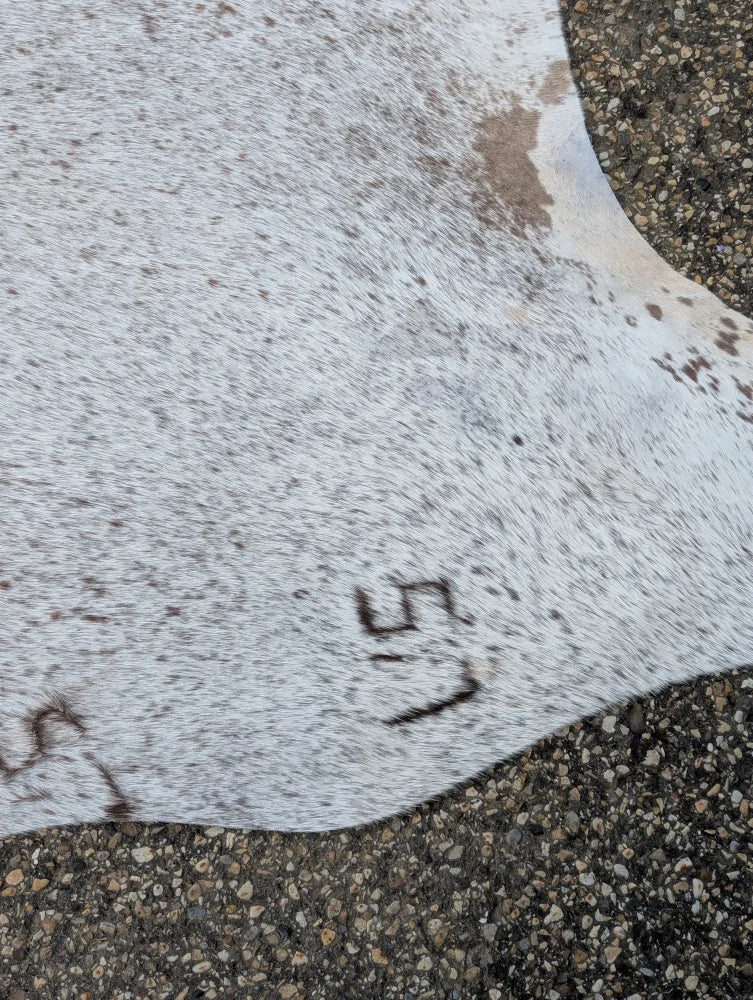 Large cowhide rug with natural brown speckles and us stamp showcasing unique characteristics for beautiful rugs